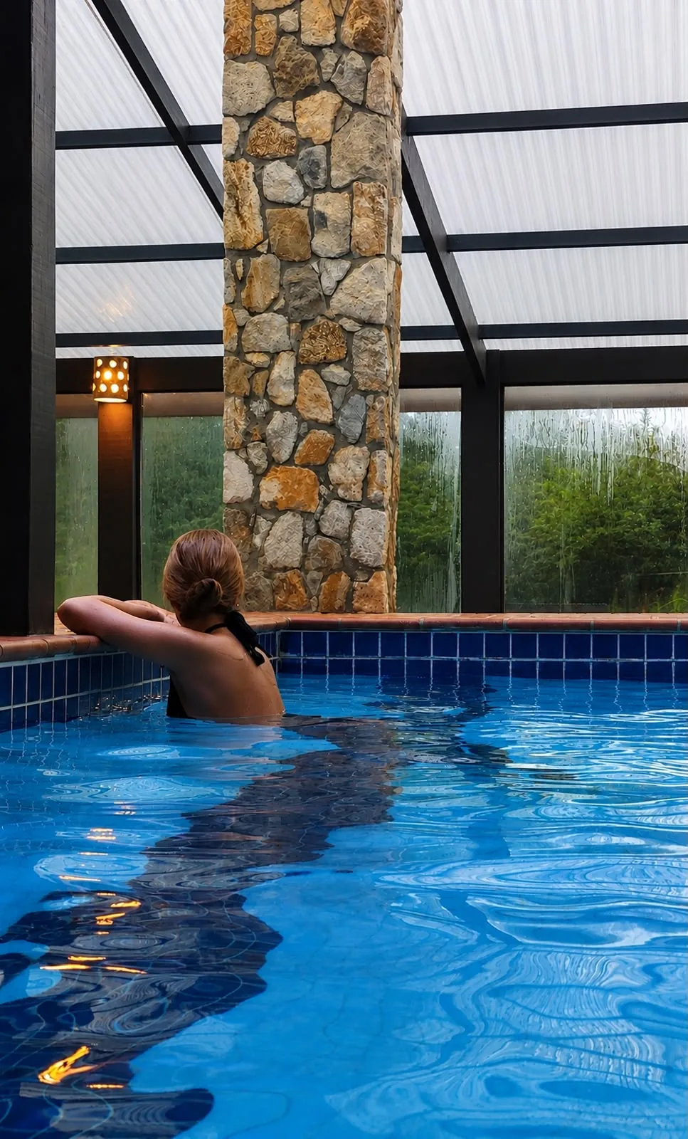 Piscina coberta e aquecida com vista para o jardim, na pousada em Monte Verde/MG