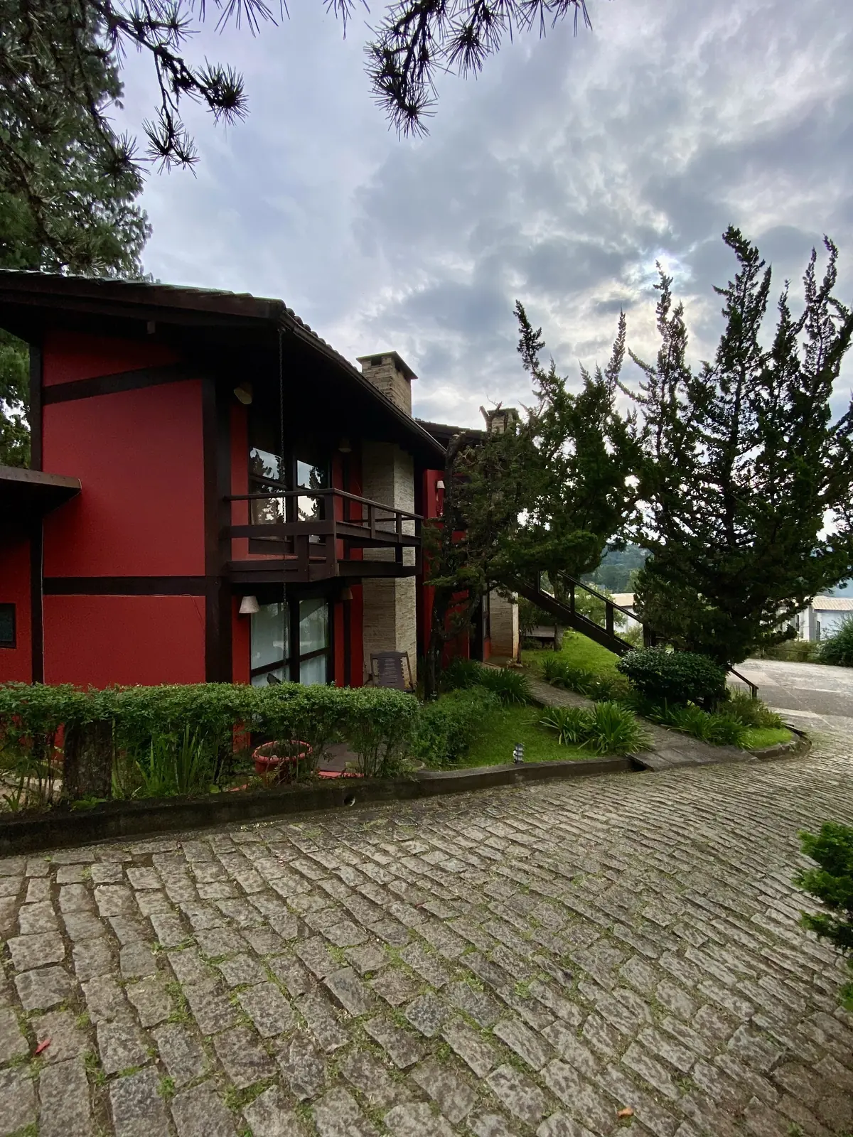 Fachada da Pousada Jardim das Montanhas em Monte Verde, com caminho de pedras entre o jardim